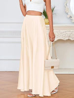 Person wearing a white top and beige skirt holding a white handbag indoors.