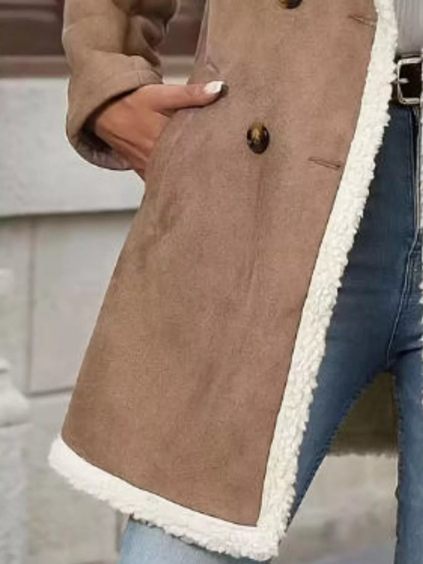 Brown coat with white trim worn by a person, blurred background