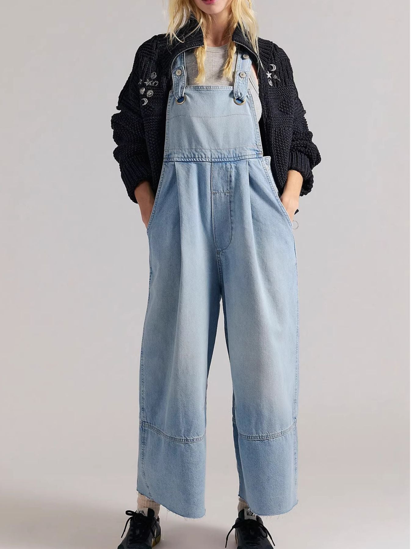 Person wearing light blue denim overalls on a plain background