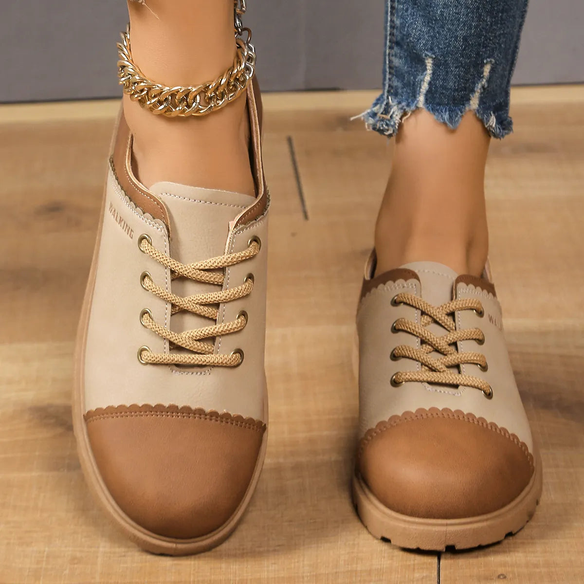 Beige and brown shoes with lace-up design on a wooden floor.