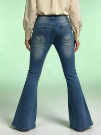 Blue flared jeans worn by a person on a light green background
