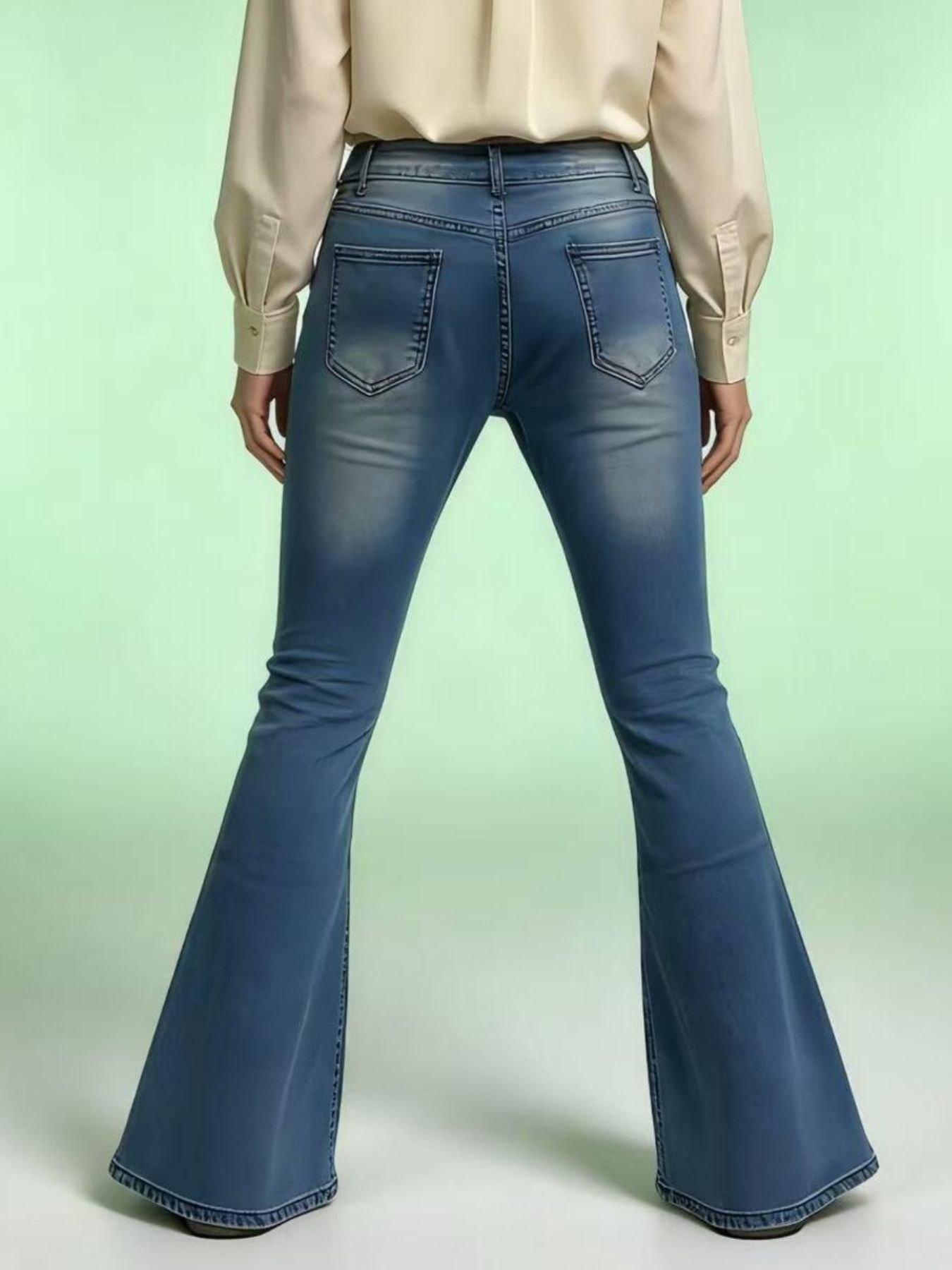 Blue flared jeans worn by a person on a light green background