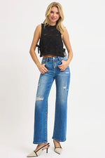 Woman wearing a black sleeveless top and blue jeans on a white background