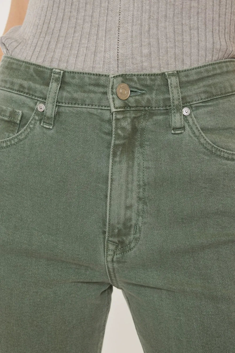 Close-up of green jeans with a neutral background