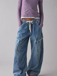 Person wearing a striped shirt and blue baggy jeans on a plain background
