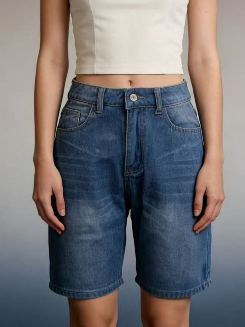 Person wearing blue denim shorts on a plain background