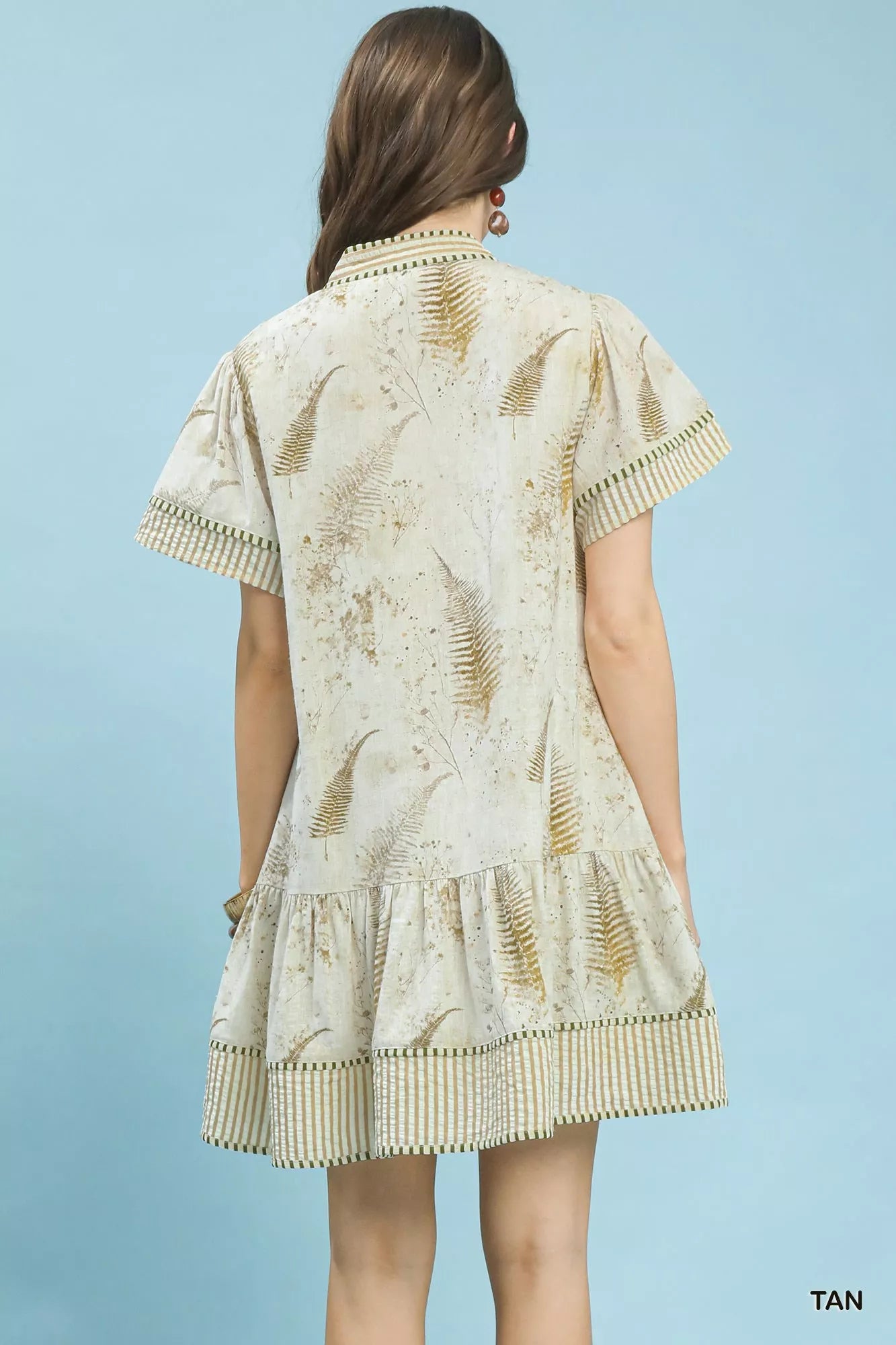 Woman wearing a patterned dress with ruffled details on a light blue background