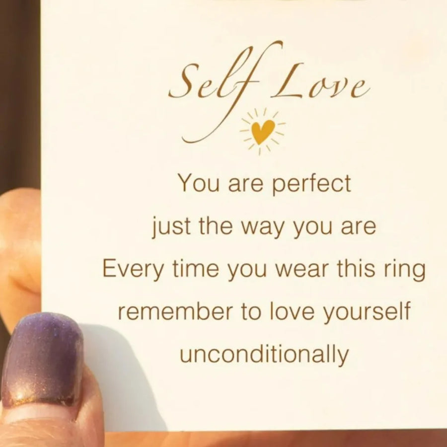 Card with 'Self Love' message and a hand wearing a ring, on a light background.