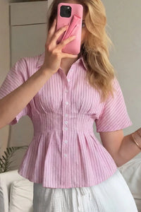 Person wearing a pink striped shirt taking a mirror selfie.