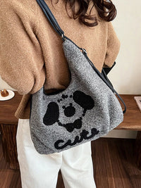 Person holding a gray bag with a black skull design and 'cute' text.