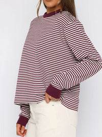 Person wearing a maroon and white striped long-sleeve top against a white background