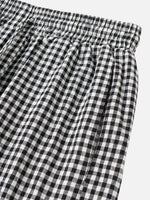 Black and white gingham checkered pants with an elastic waistband, shown in a close-up detail shot against a light gray background.