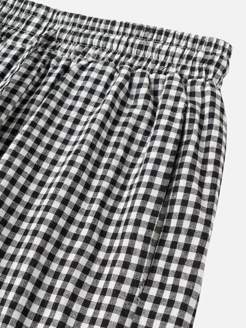 Black and white gingham checkered pants with an elastic waistband, shown in a close-up detail shot against a light gray background.