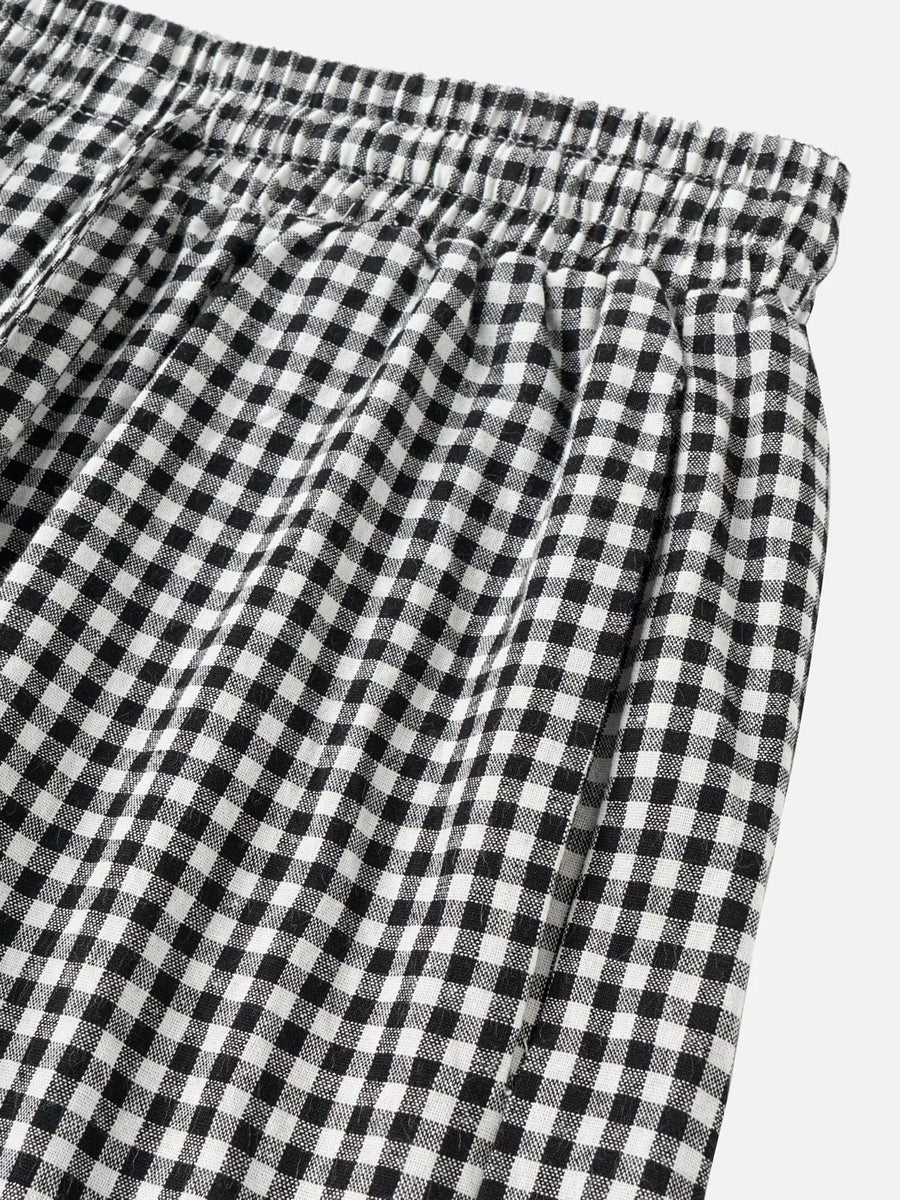 Black and white gingham checkered pants with an elastic waistband, shown in a close-up detail shot against a light gray background.