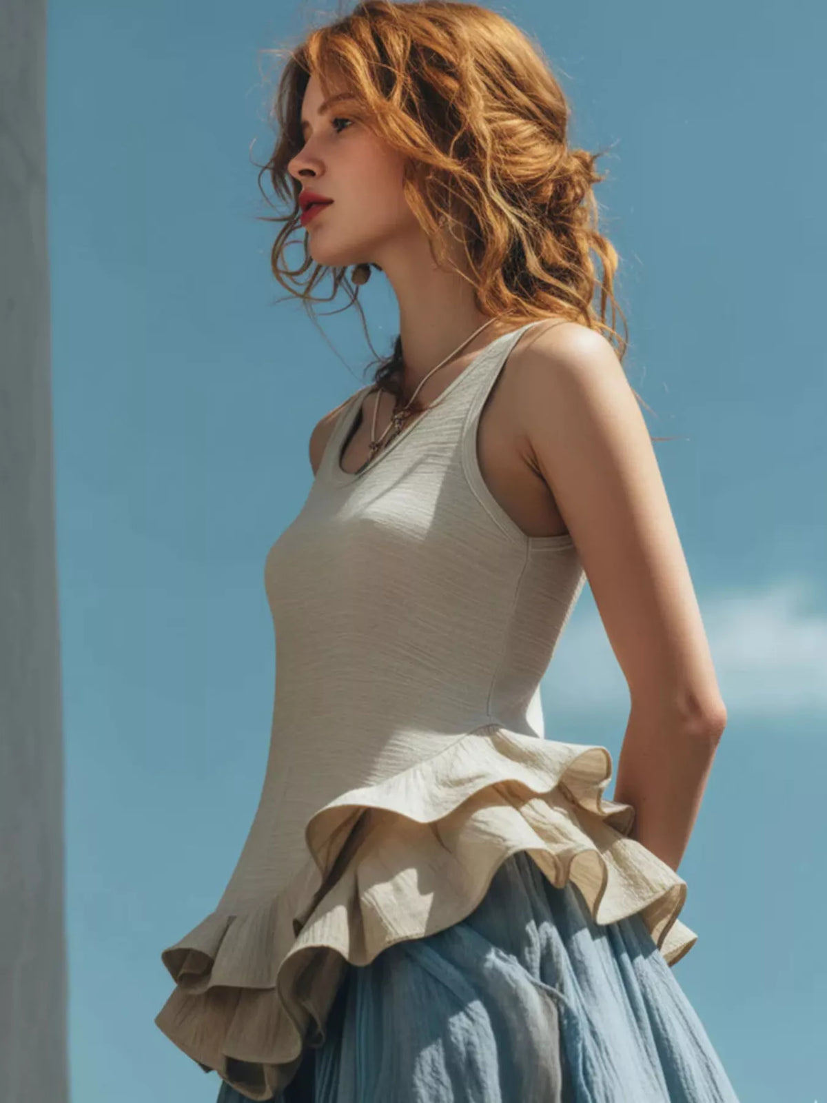 Woman wearing a beige ruffled top against a blue sky