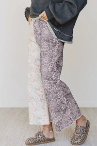 Person wearing leopard print pants and shoes on a plain background