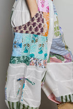 Colorful patchwork dress with floral and abstract patterns on a plain background