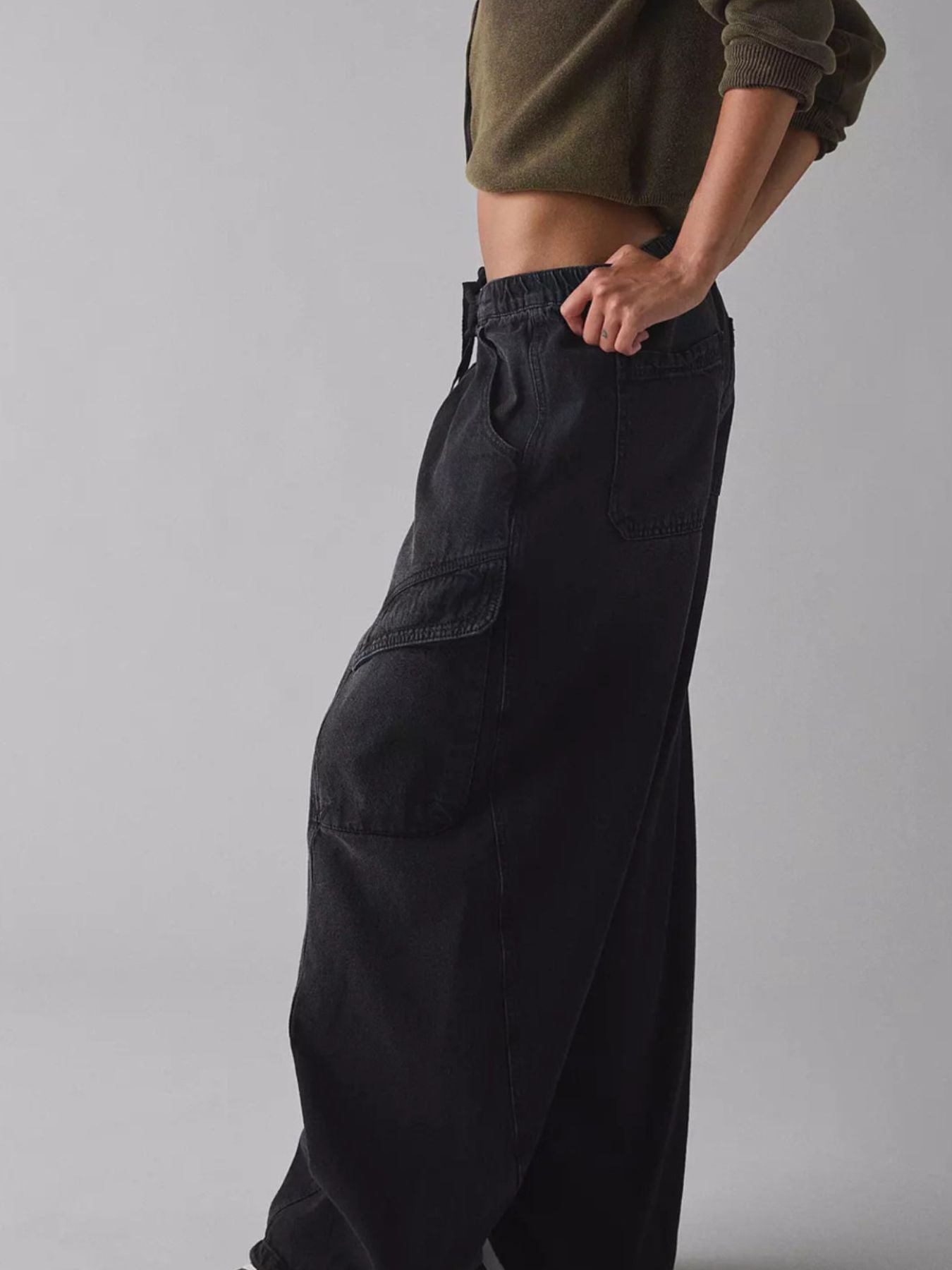 Person wearing black cargo pants on a gray background