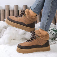 Brown winter boots with fur lining worn by a person in the snow.