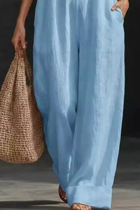 Person wearing light blue pants holding a woven bag on a dark background