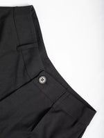 Close-up of black pants with a button on a white background