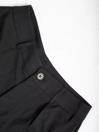 Close-up of black pants with a button on a white background