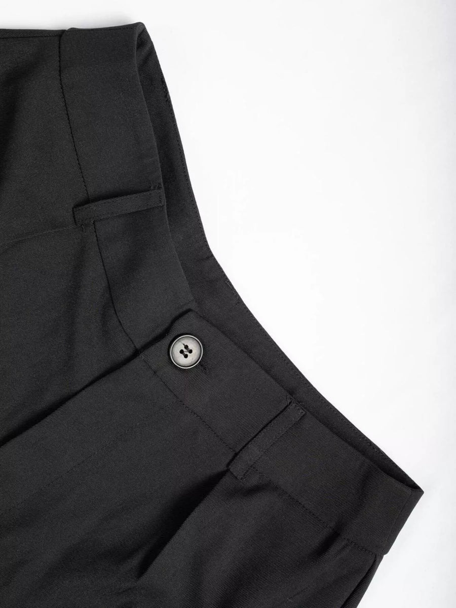 Close-up of black pants with a button on a white background