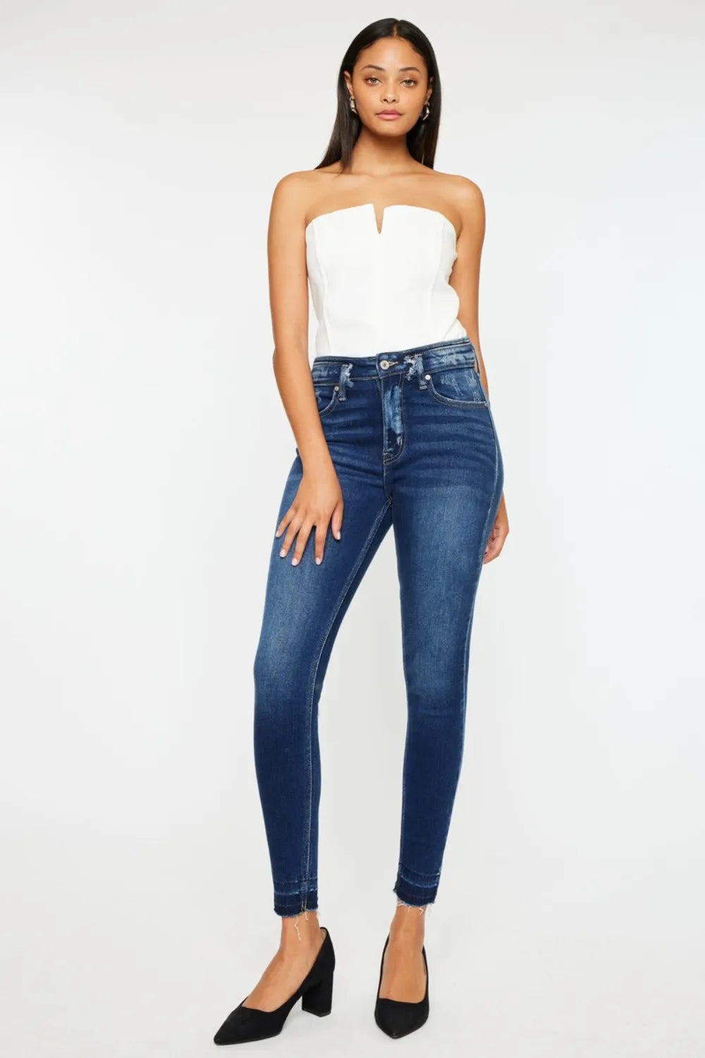 Woman wearing a white strapless top and blue jeans on a white background