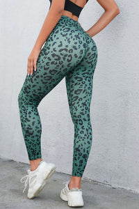 Person wearing green leopard print leggings against a gray wall.