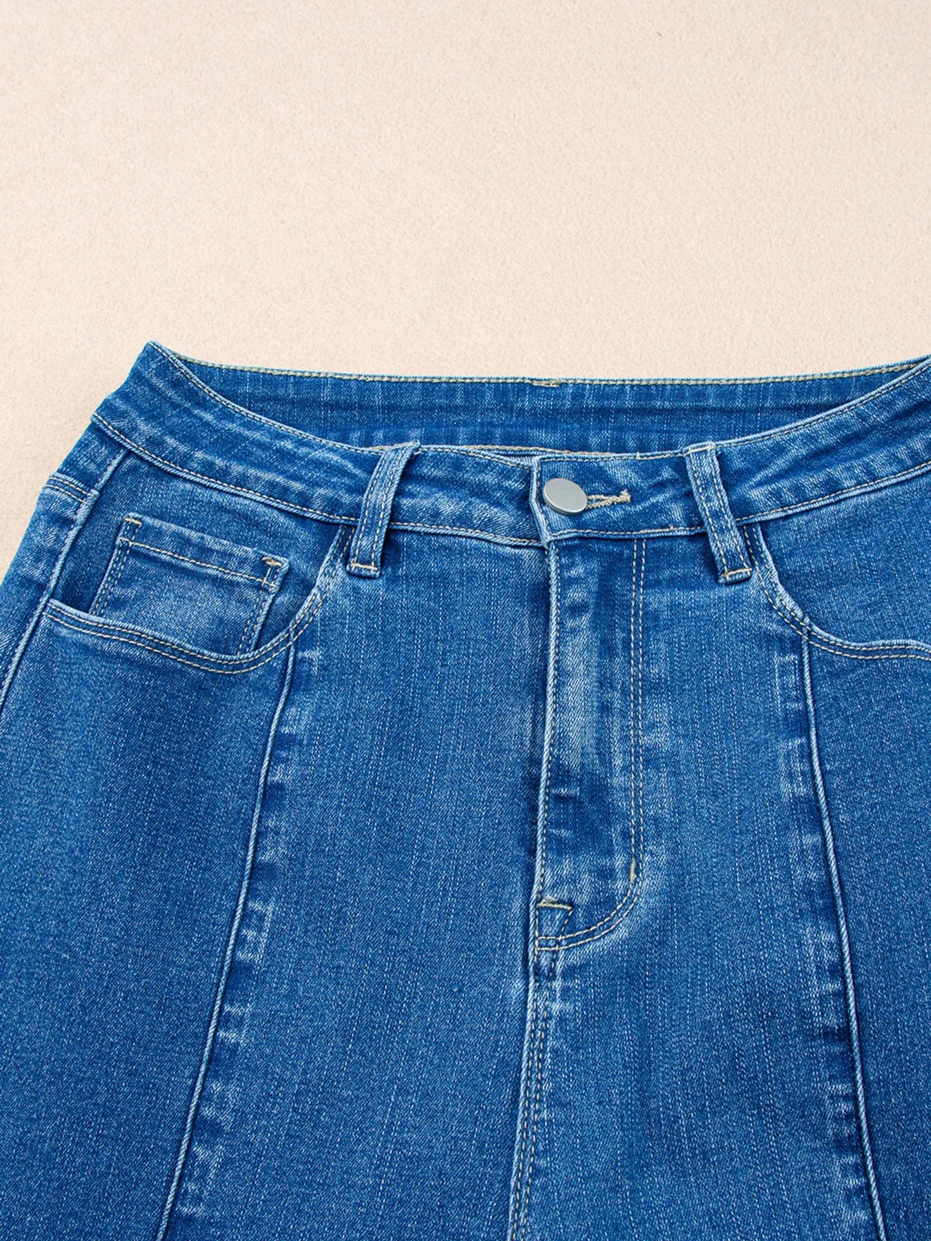 Close-up of blue denim jeans on a beige background