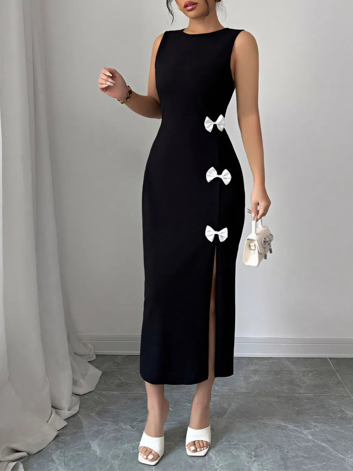 Black dress with white bow details worn by a model against a plain background