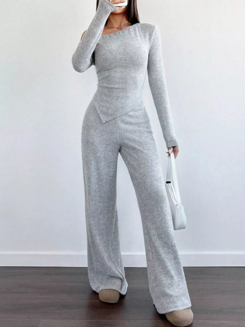 Person wearing a gray jumpsuit against a white background