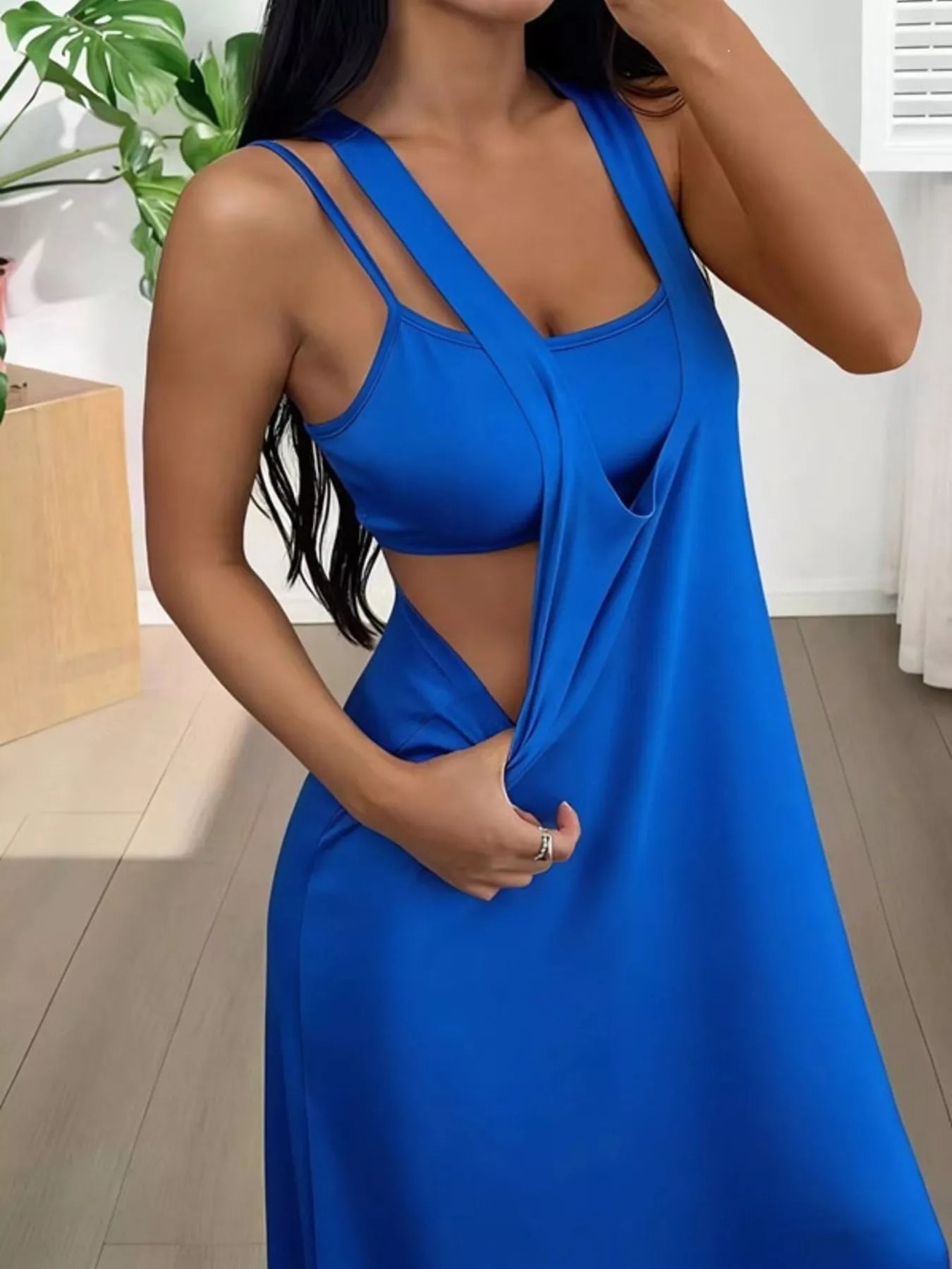 Woman wearing a blue dress with a plunging neckline in an indoor setting.