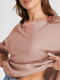 Person wearing a pink textured sweater with a plain background