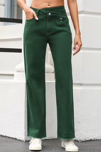 Person wearing green pants standing against a white wall.