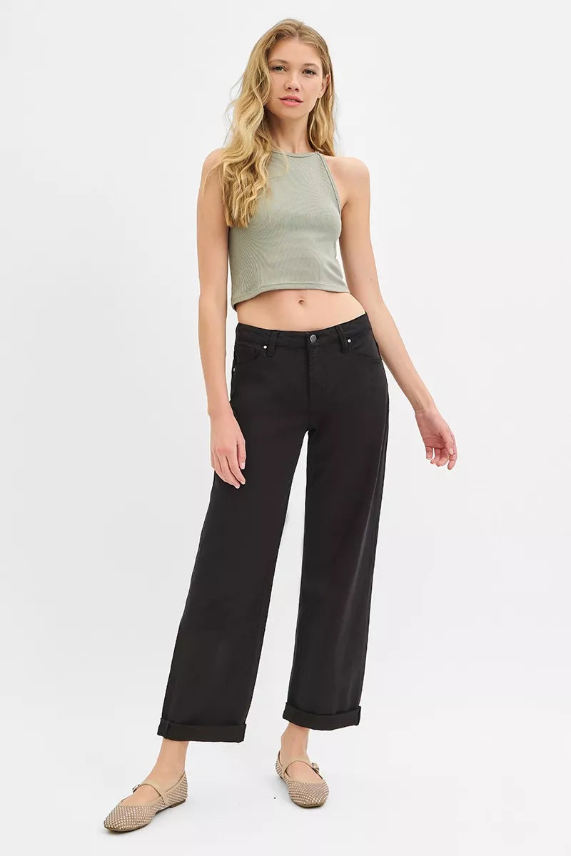 Woman wearing a green top and black pants on a white background