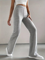 Person wearing gray ribbed pants and white sneakers on a plain background