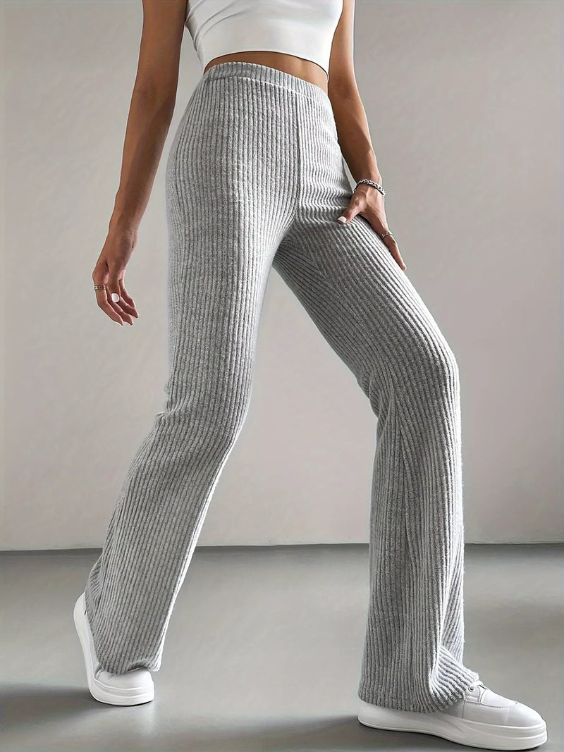 Person wearing gray ribbed pants and white sneakers on a plain background