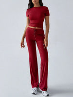 Woman wearing a red outfit with a crop top and wide-leg pants on a white background