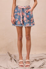 Person wearing blue floral shorts on a beige background