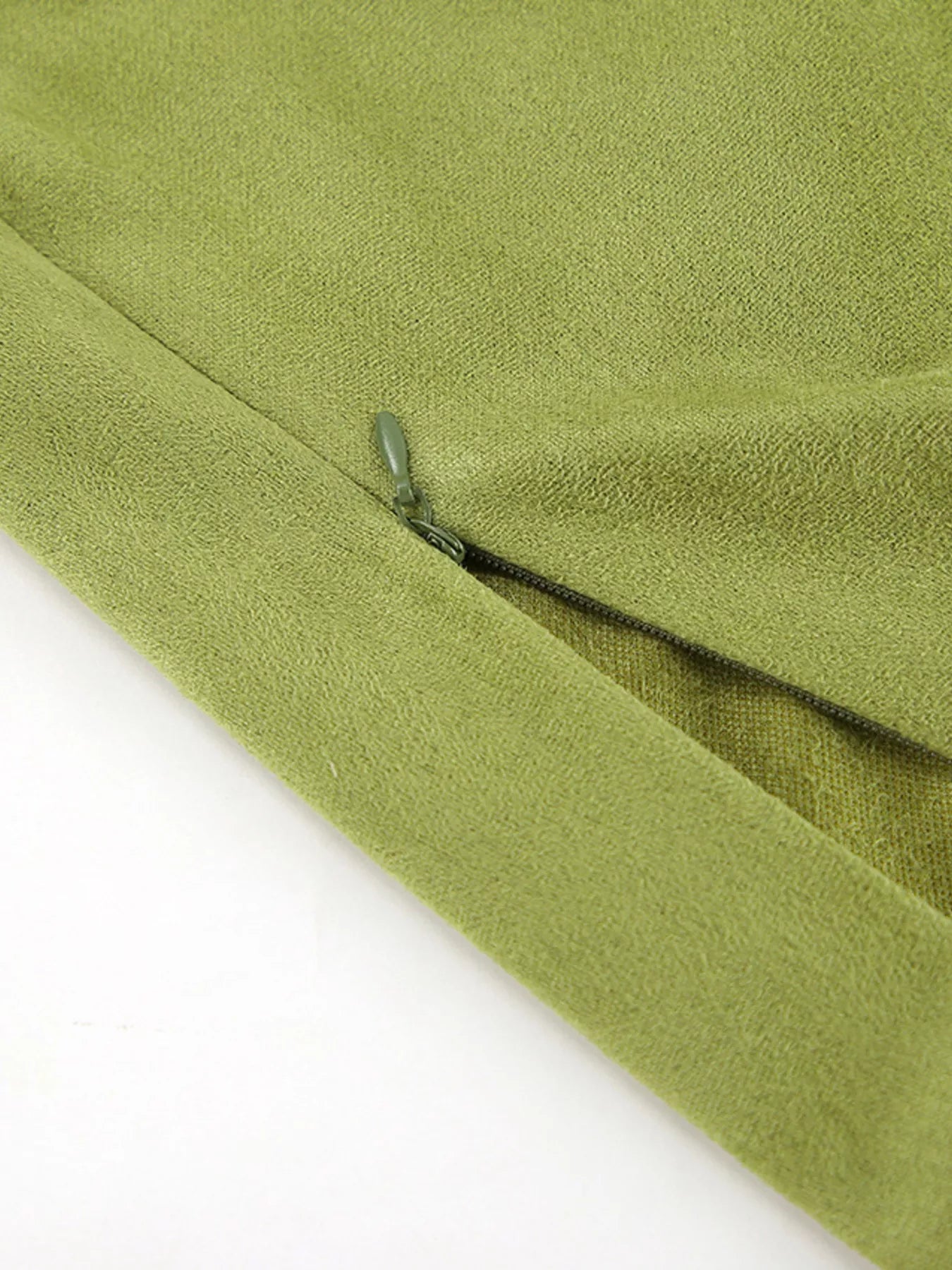 Close-up of a green fabric with a zipper on a white background