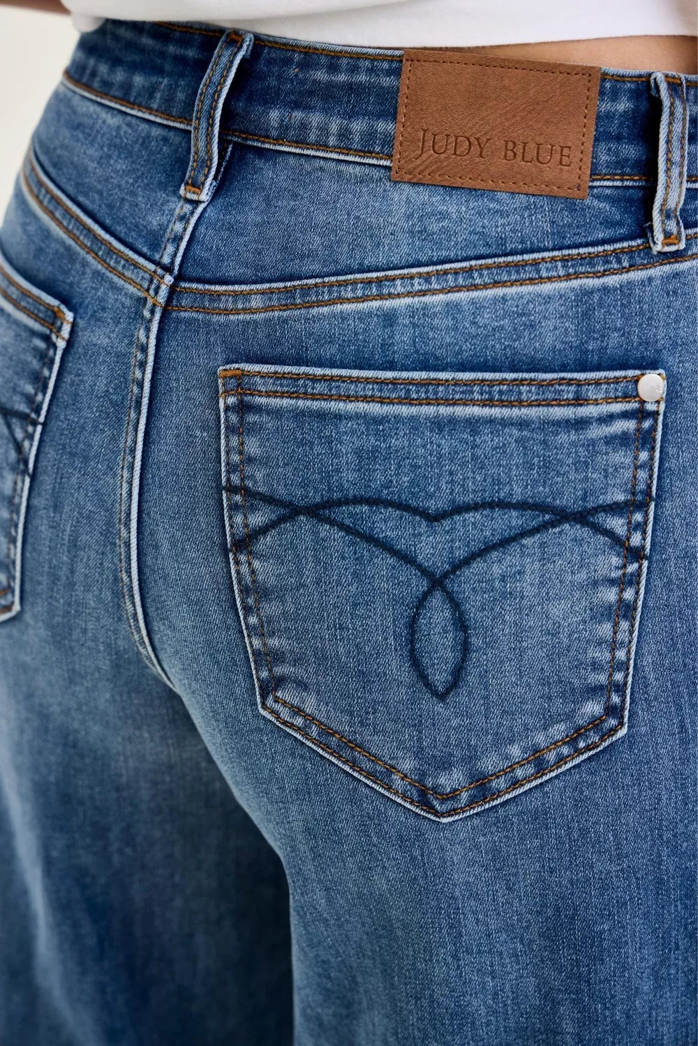 Close-up of blue jeans with a brand label on the back pocket.