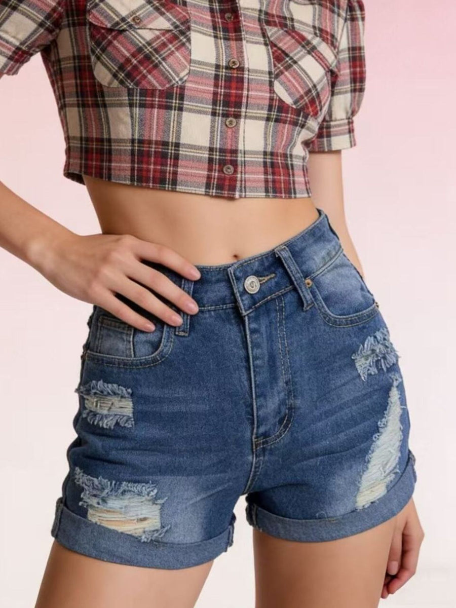 Person wearing a plaid crop top and denim shorts on a pink background