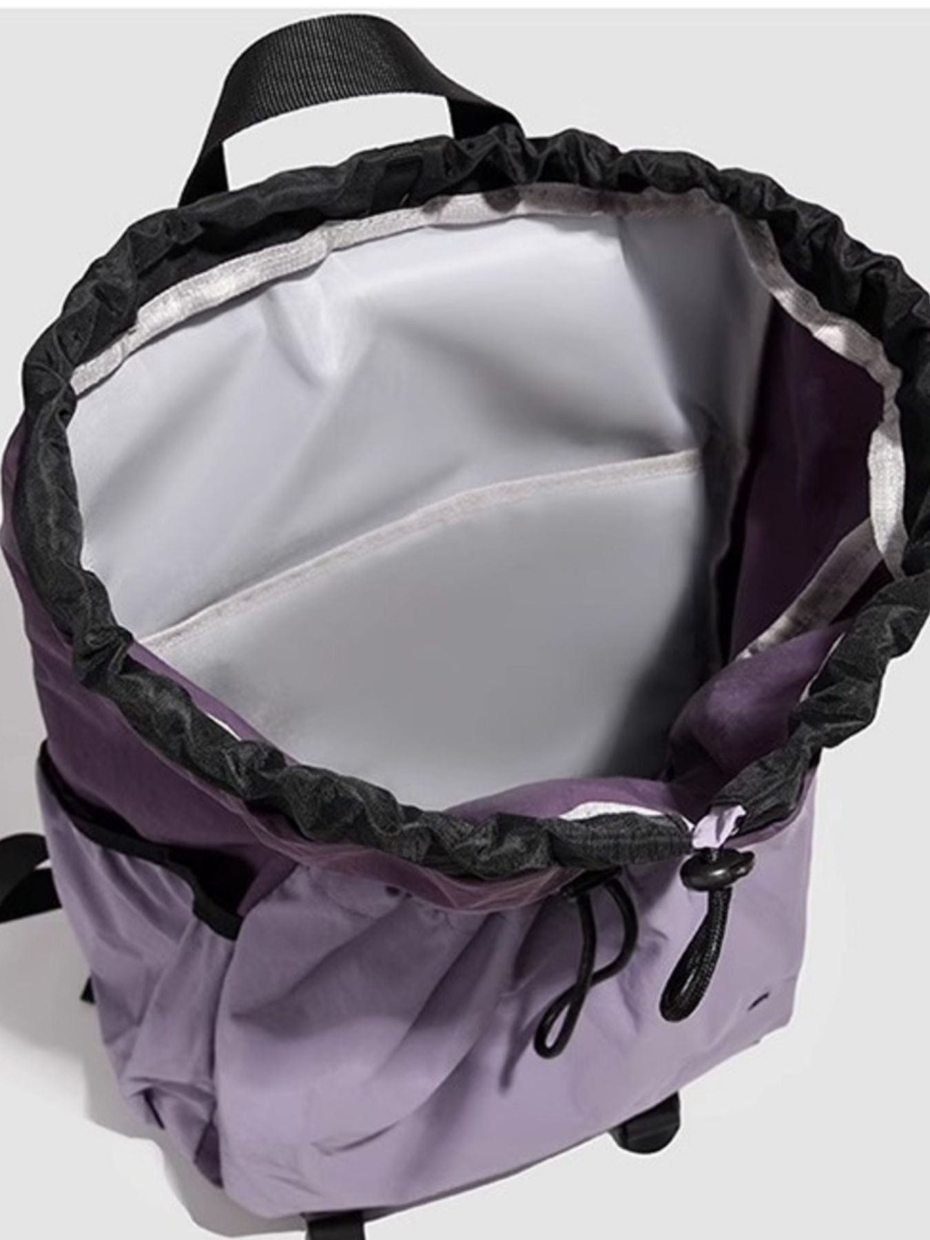 Purple backpack with black interior and straps on a white background