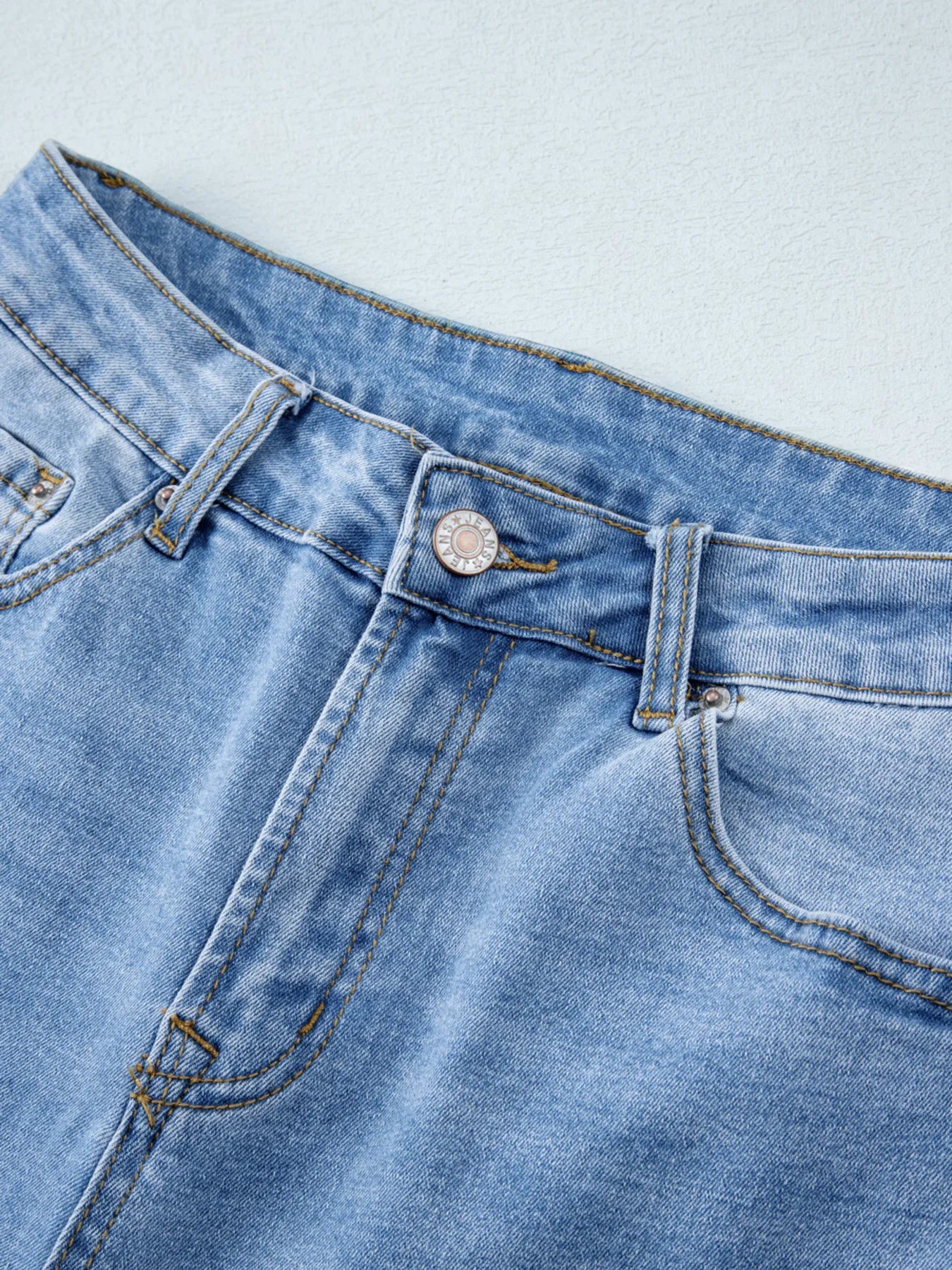 Close-up of blue denim jeans on a light gray background