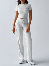 Person wearing a gray crop top and pants set on a white background