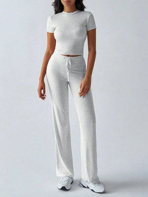 Person wearing a gray crop top and pants set on a white background