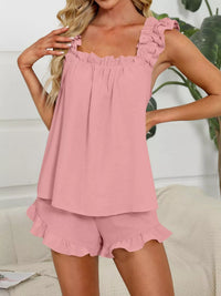 Woman wearing a pink pajama set with ruffled details in a home setting.