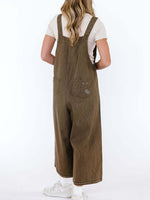 Person wearing brown overalls on a white background