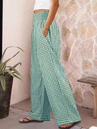 Person wearing green checkered pants standing against a stone wall.